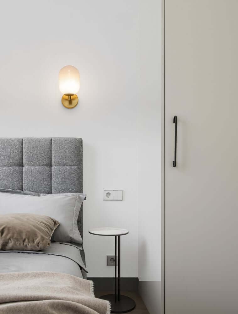 Elegante Balor Wandleuchte Gold neben einem Bett in modernem Schlafzimmer-Design.
