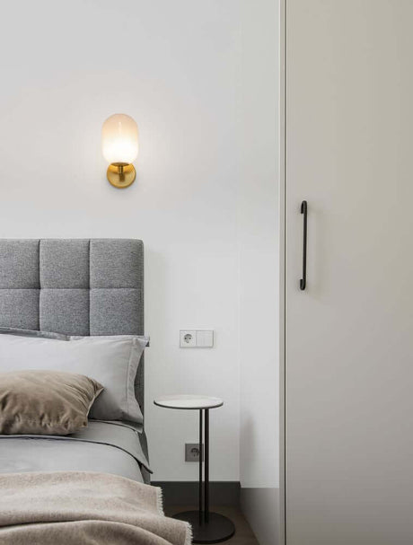 Elegant Balor wall light gold next to a bed in a modern bedroom design.