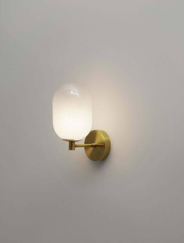 Balor Wandleuchte Gold an einer Wand montiert mit opalglas Leuchtmittel und modernem Design.