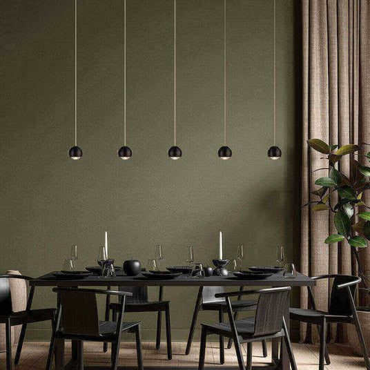 Elegantes Esszimmer mit modernen hängenden Lampen, schwarzem Tisch und Stühlen, stilvolles grün als Hintergrund.