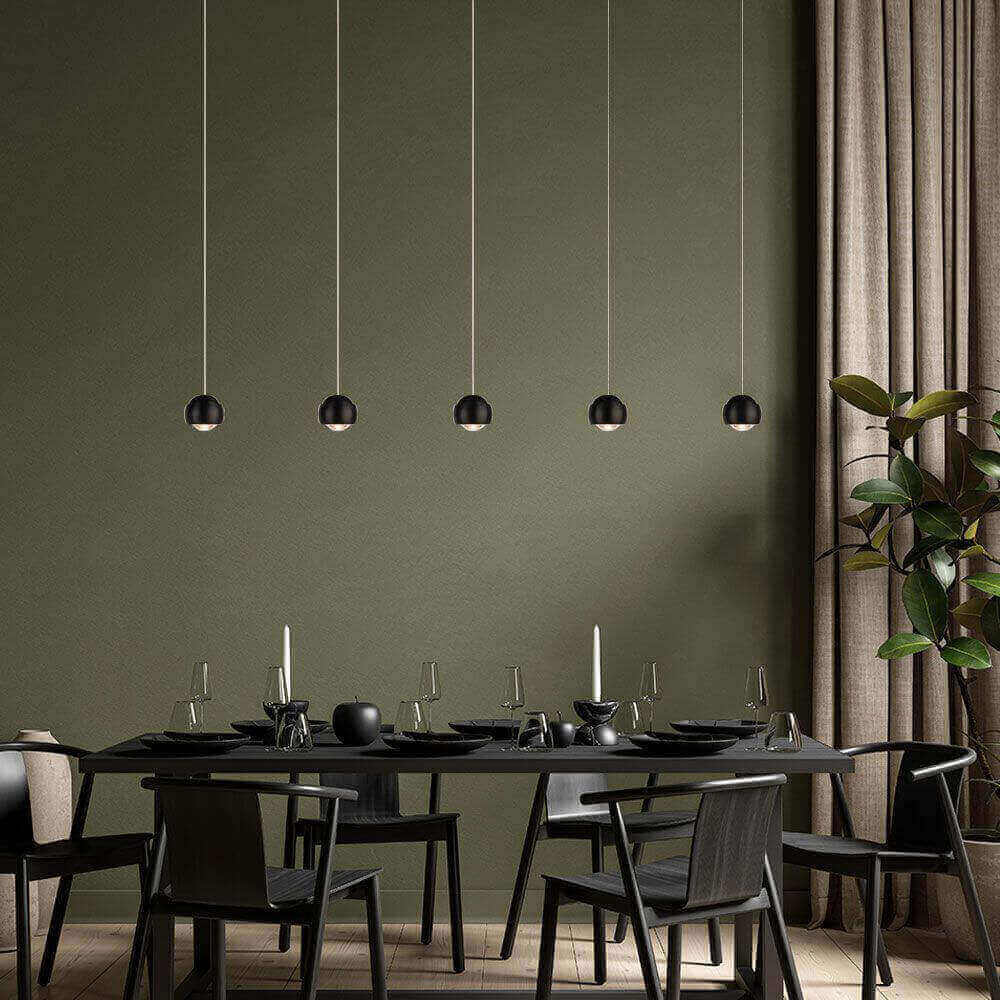 Elegantes Esszimmer mit modernen hängenden Lampen, schwarzem Tisch und Stühlen, stilvolles grün als Hintergrund.