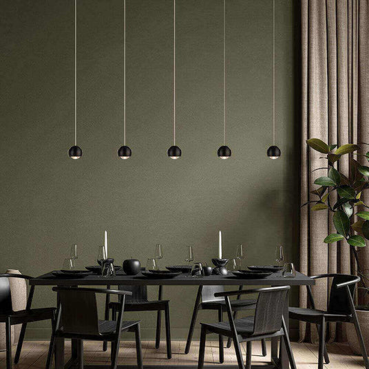 Elegantes Esszimmer mit modernen hängenden Lampen, schwarzem Tisch und Stühlen, stilvolles grün als Hintergrund.