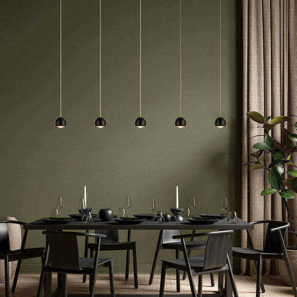 Elegantes Esszimmer mit modernen hängenden Lampen, schwarzem Tisch und Stühlen, stilvolles grün als Hintergrund.