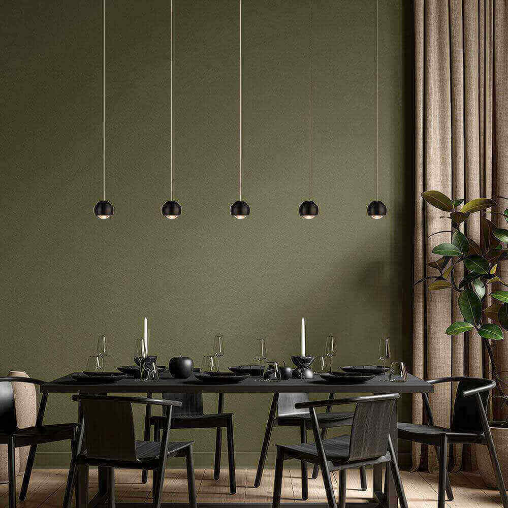 Elegantes Esszimmer mit modernen hängenden Lampen, schwarzem Tisch und Stühlen, stilvolles grün als Hintergrund.