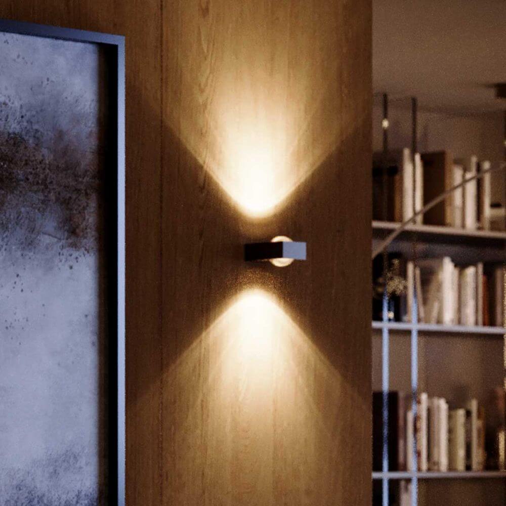 s.luce Beam X moderne Wandleuchte Up & Down eckig an einer Holzwand mit Lichtkegeln