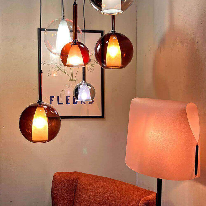 Moderne hängende Lampen in verschiedenen Farben über einem orangefarbenen Sofa in einem stilvollen Raum.