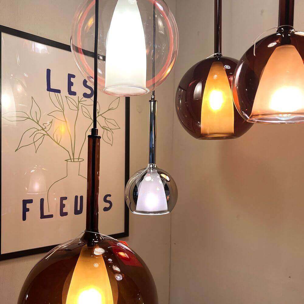 Moderne Pendelleuchten in verschiedenen Formen und Farben, dekoriert mit einem Kunstwerk im Hintergrund.