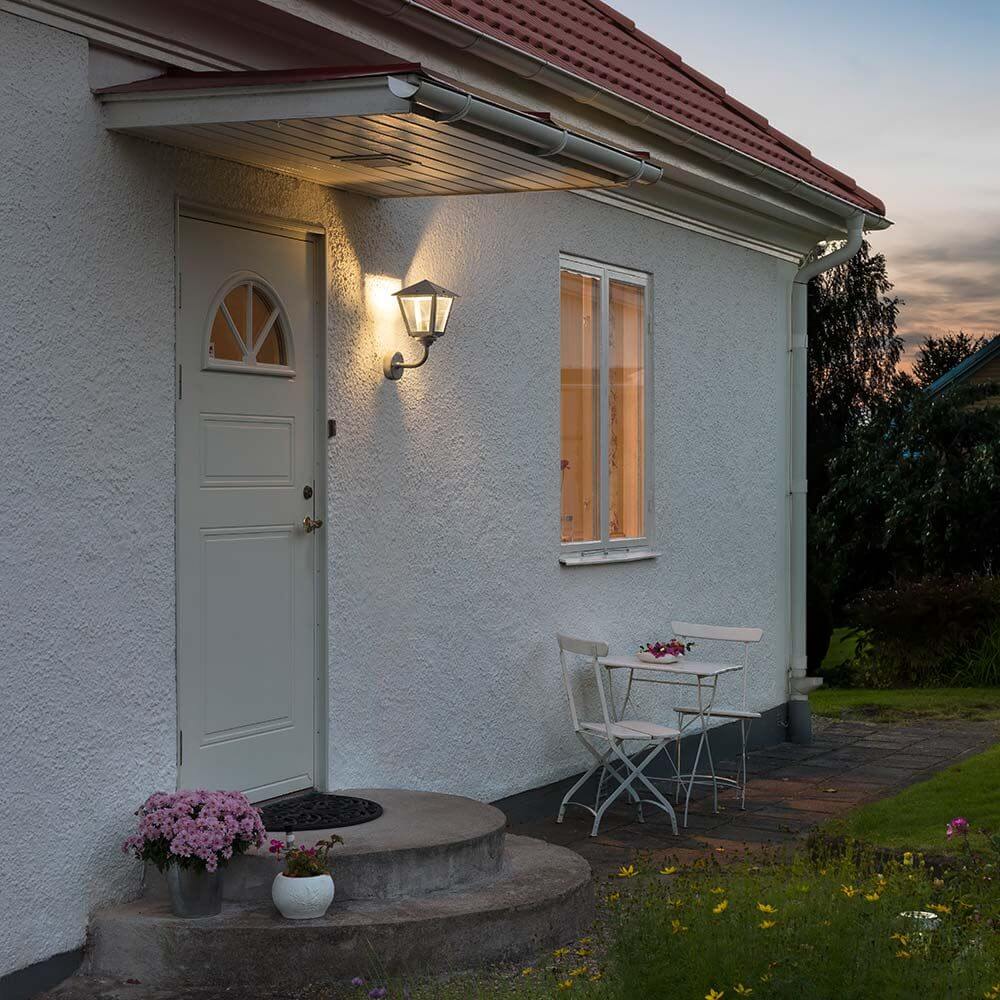 Benu LED Außen-Wandlampe 3000K galvanisierter Stahl, klares Glas an einem Eingangsbereich mit Blumen.