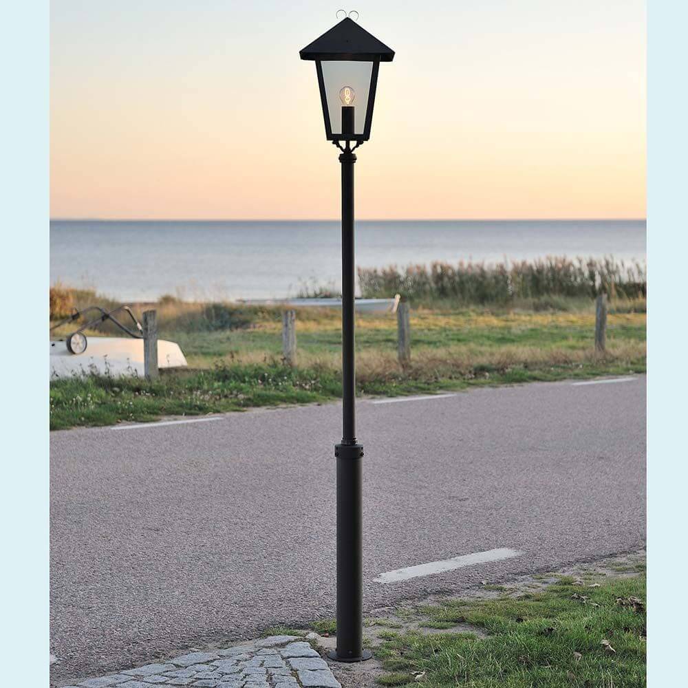 Benu Mastleuchte 254cm Schwarz, rauchfarbenes Acrylglas im Freien auf einem Weg mit Meerblick.