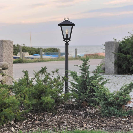 Benu lampada da giardino nera, vetro acrilico fumé all'aperto con piante e mare sullo sfondo.
