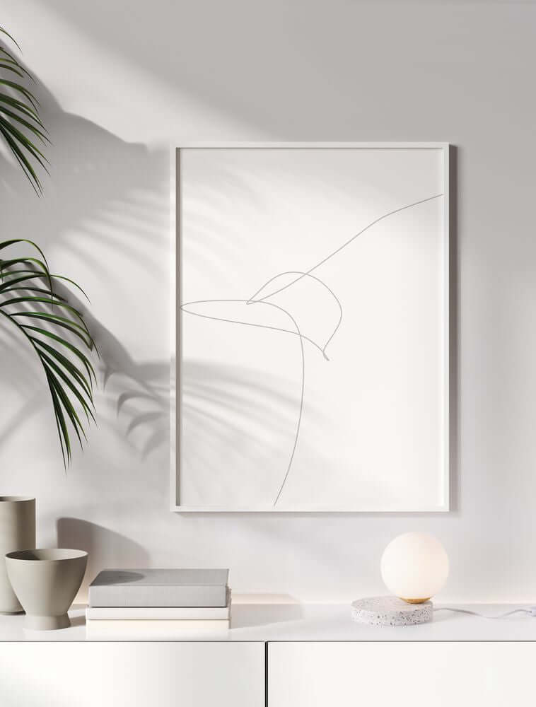 Minimalistisches Kunstwerk mit Linienzeichnung in einem modernen Rahmen, umgeben von Pflanzen und dekorativen Elementen.