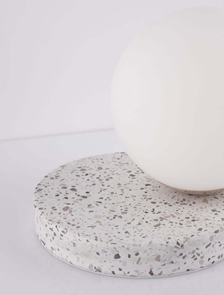 Beson Tischleuchte H 18cm Grau, Weiß auf einem terrazzo Untergrund mit Kugel aus weißem Material.