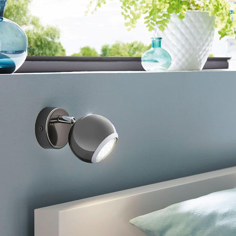 Bimeda Spot Ø 7cm nickel-noir, chrome - applique moderne sur mur bleu avec des vases décoratifs en arrière-plan.