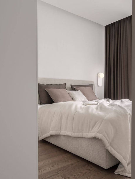 Vue moderne d'une chambre à coucher avec applique murale Blob G9 et linge de lit élégant.
