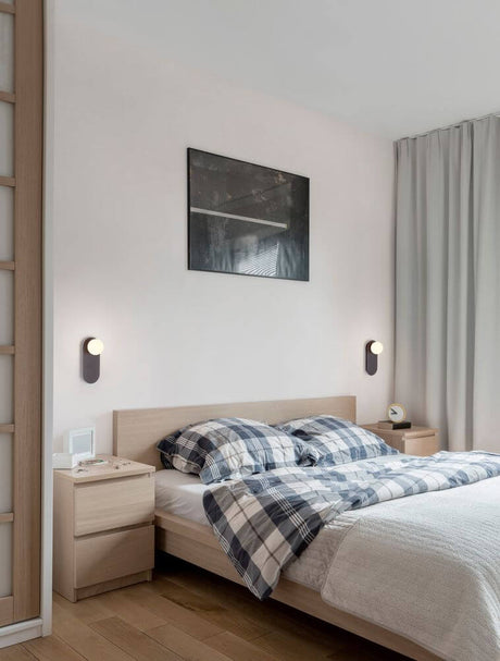 Chambre à coucher chaleureuse avec applique murale Blob G9 à côté du lit et éléments décoratifs modernes.