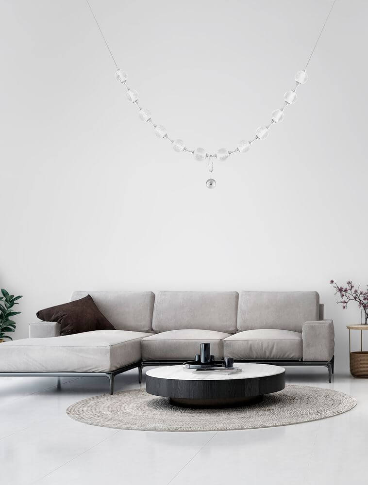 Brillante LED Pendelleuchte 12-flammig 3200K über modernem Wohnzimmer mit grauem Sofa und runder Tischdekoration.