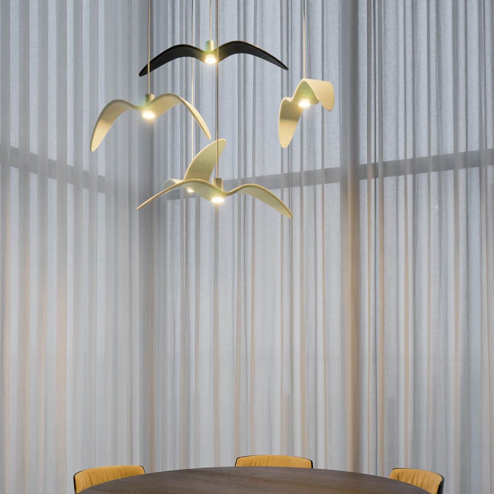 Brokis Hängeleuchte Night Birds waagrechte Flügel 78cm in modernem Raum mit Tisch und Vorhängen.