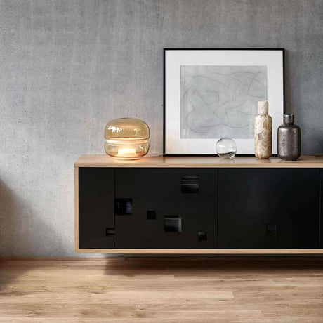 Brokis Tischlampe Macaron S auf einem modernen Sideboard mit Kunst und Dekoration.