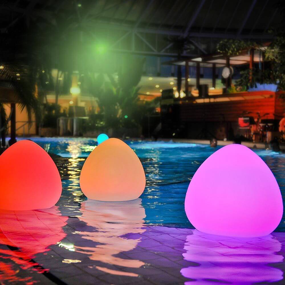 Bunte LED-Akkuleuchten Stone im Wasser bei Nacht, schaffen eine entspannte Atmosphäre im Garten oder Poolbereich.