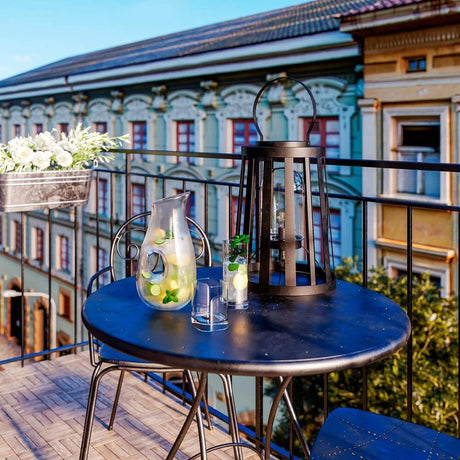 Außenlampe Delphia Tisch- & Bodenlampe IP44 auf einem Balkon mit Getränken und dekorativer Pflanzen.