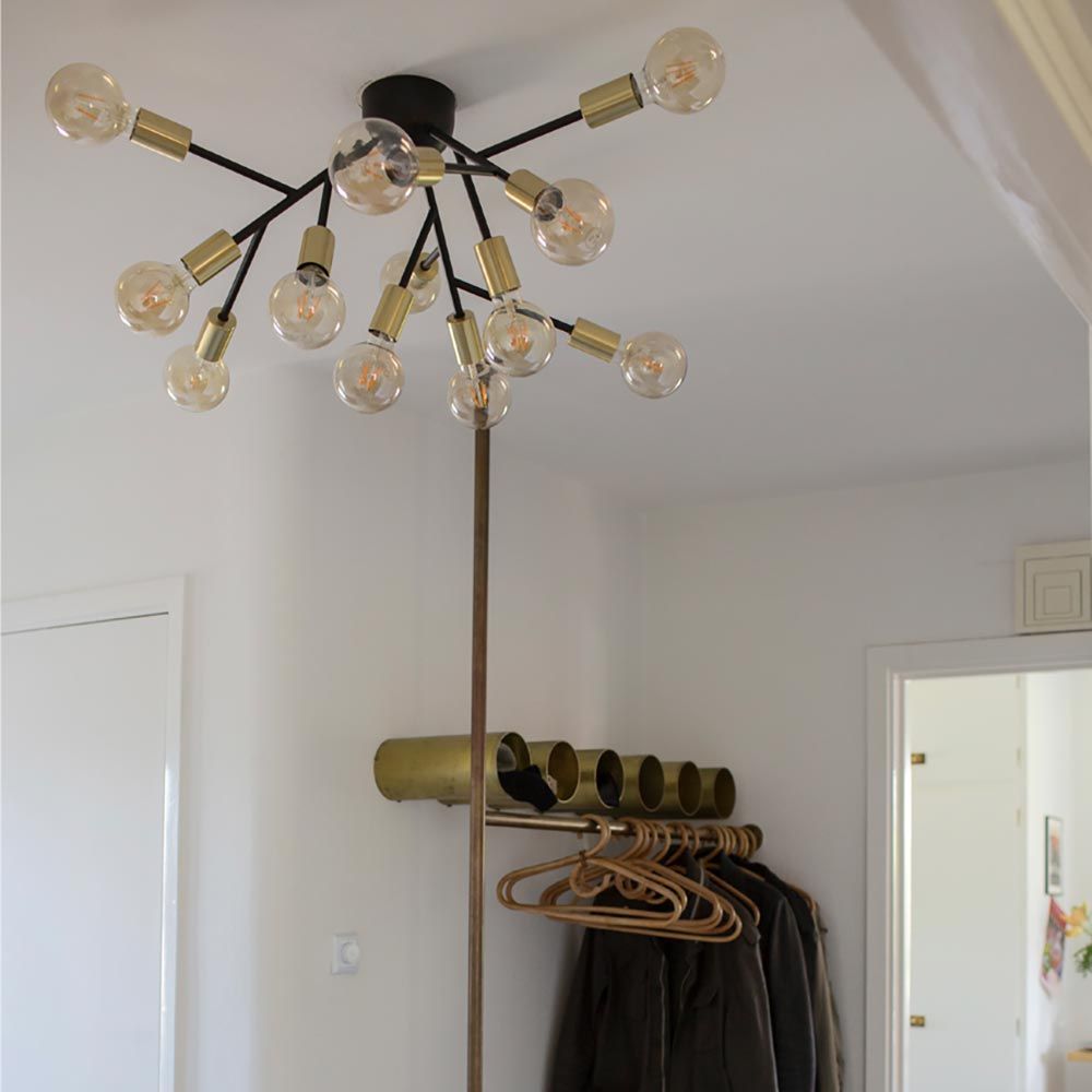 Taklampe Heroes med 12 lyskilder i svart i et moderne interiør med klare lyspærer.