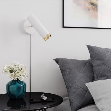 Faretto da parete Puls bianco accanto a un comodino con fiori e cuscini, ideale per un'illuminazione accogliente.
