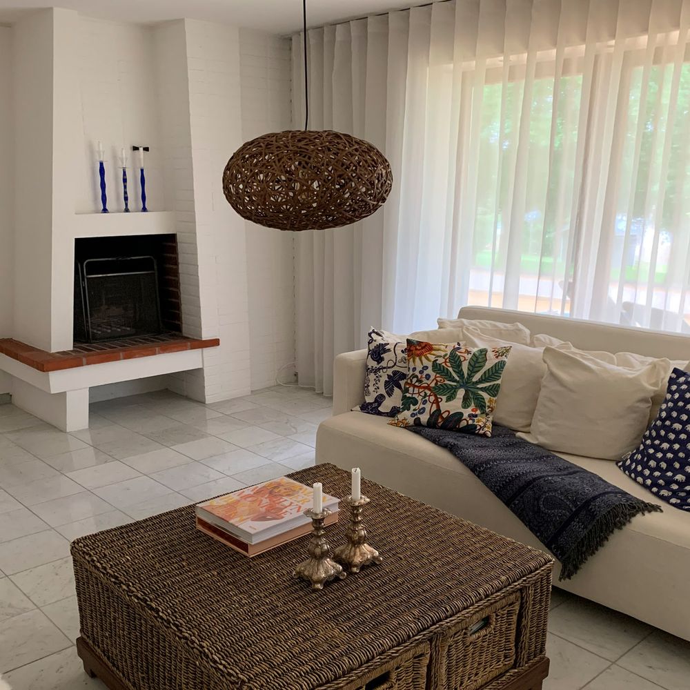 Rustikale Hängeleuchte Diego aus Rattan in modernem Wohnzimmer über Couchtisch und Sofa.