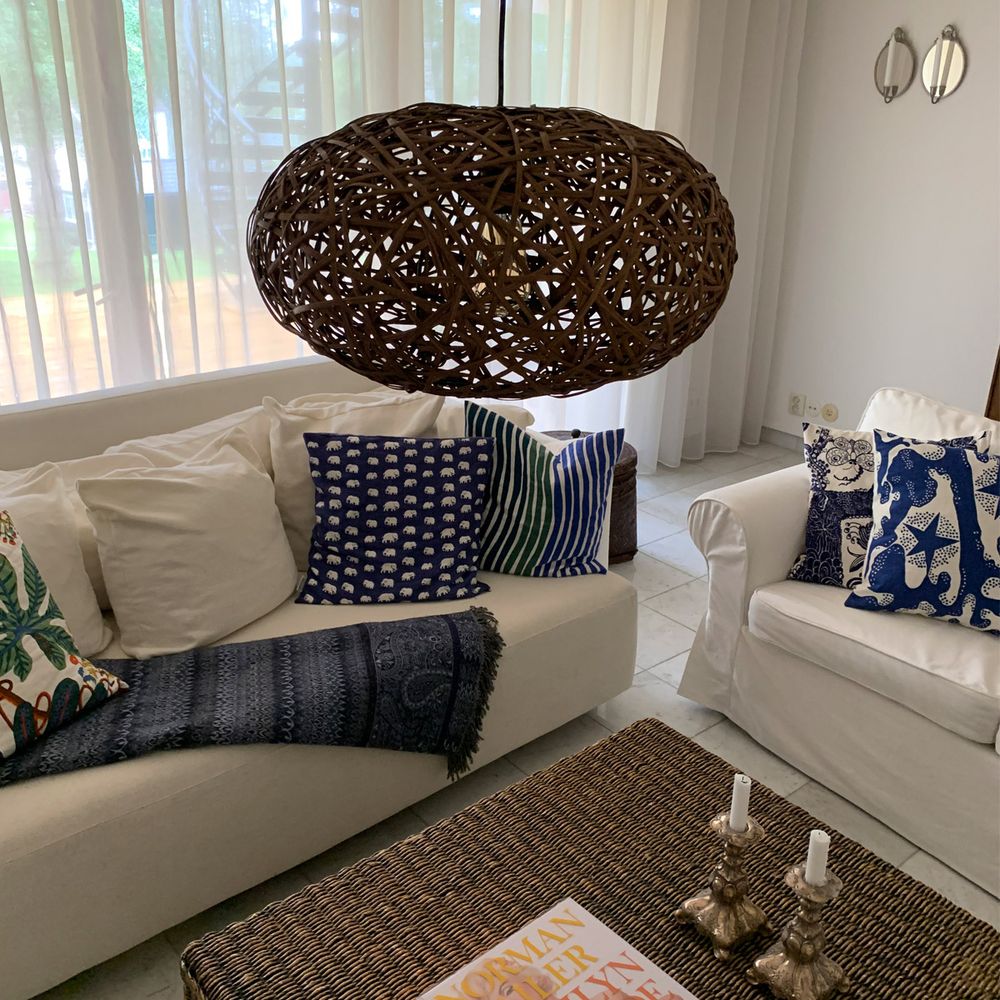 Handgefertigte Hängeleuchte „Diego“ aus Rattan über einer hellen Wohnzimmereinrichtung.