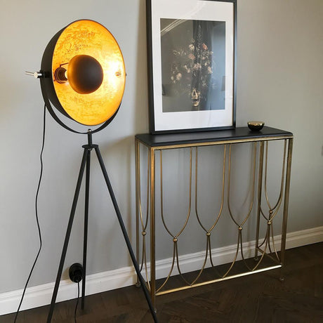 Captain Mini tripod floor lamp next to a modern console table and artwork on the wall in a stylish room.