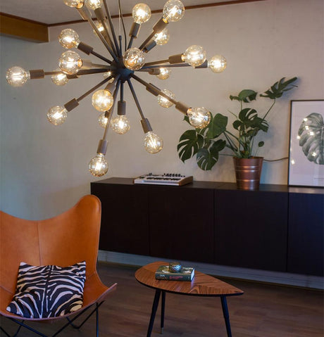 Suspension Leo à 24 feux dans un espace de vie moderne avec un fauteuil et des plantes à l'arrière-plan.