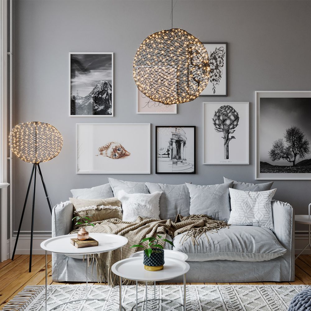 Hayden LED Stehleuchte neben Sofa und Bildern in modernem Wohnzimmer. Elegantes Design mit handgefertigtem Metallnetz.