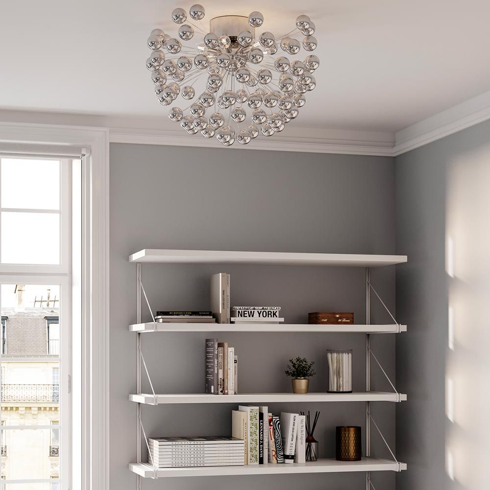 LED-taklampe Carroll Ø 58 cm krom i stuen over en bokhylle.