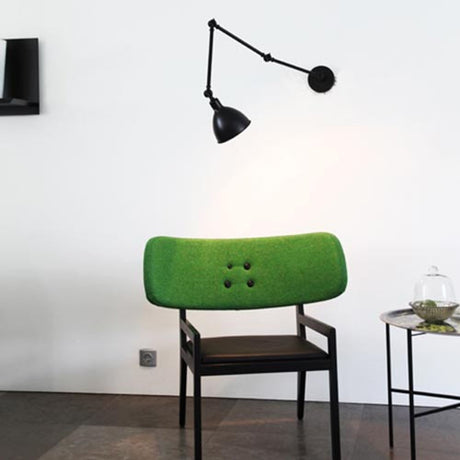 Applique da lettura Bazar bianco sabbia accanto a una moderna sedia verde in un arredamento minimalista.