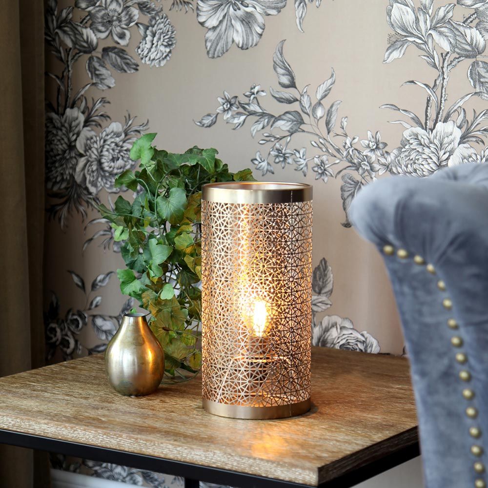 Tischleuchte Hermine 28cm Messing auf einem Tisch neben einer Pflanze und einer dekorativen Vase.