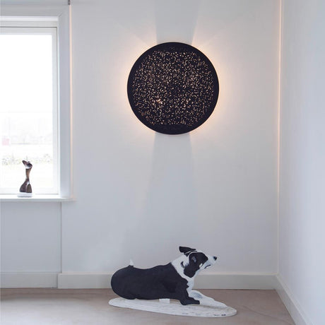 Væglampe Colby Ø 70cm på væggen med perforerede huller og en hund i et moderne rum.