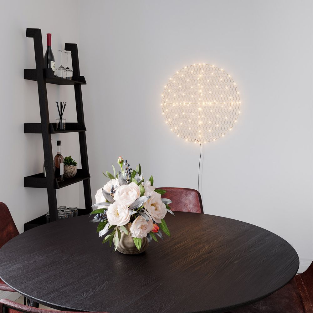 Wandlampe Hayden Ø 70cm über einem runden Tisch mit Blumenstrauß in einem modernen Wohnraum.