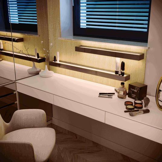 Moderne Schminkstation mit Spiegel, Beleuchtung und Make-up-Zubehör auf dem Tisch.