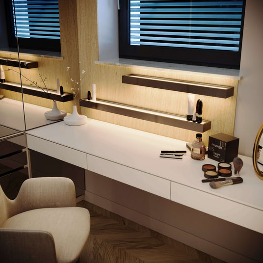 Moderne Schminkstation mit Spiegel, Beleuchtung und Make-up-Zubehör auf dem Tisch.