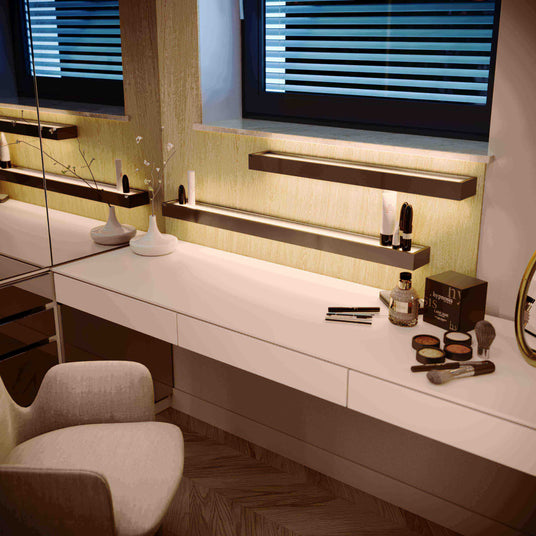 Moderne Schminkstation mit Spiegel, Beleuchtung und Make-up-Zubehör auf dem Tisch.