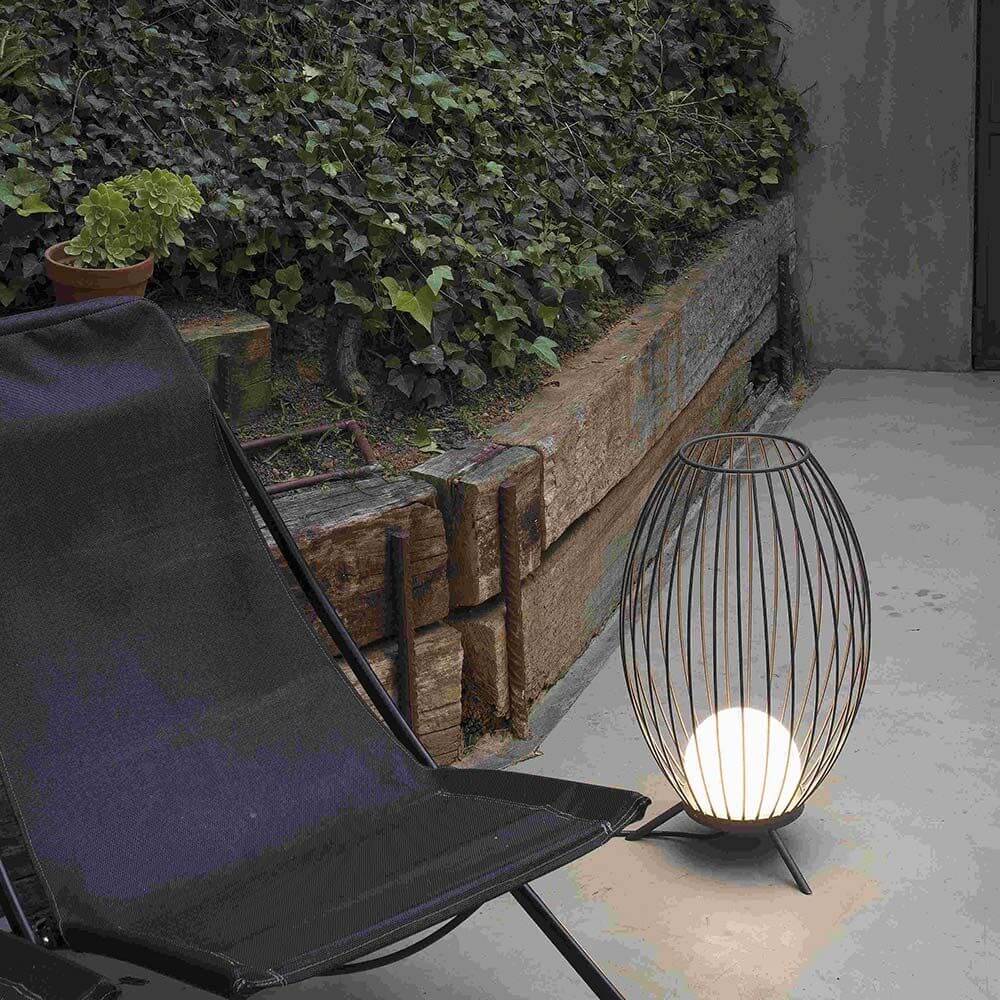 Cage Outdoor LED Terrassenlampe IP65 Anthrazit neben einem Liegestuhl im Außenbereich.