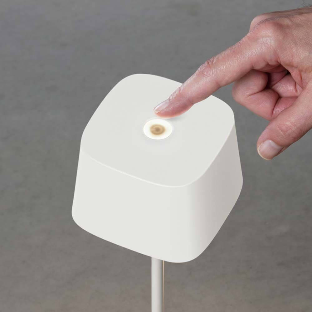 Hand, die die Capri USB-Tischleuchte IP54 berührt, um die dimmbare Lichtstärke zu regulieren.