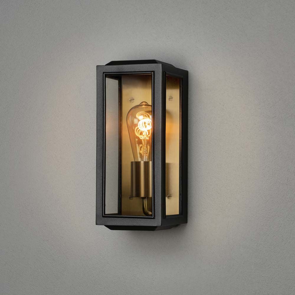 Außen Wandleuchte Carpi im Vintage-Look IP44 an grauer Wand montiert mit Glühbirne im Inneren.