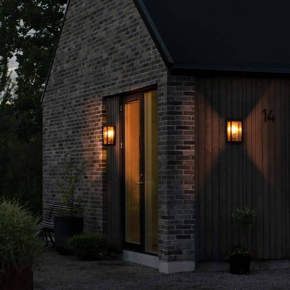 Carpi Wandleuchte Stahl IP44 an einer modernen Hauswand, warmes Licht beleuchtet den Eingang.