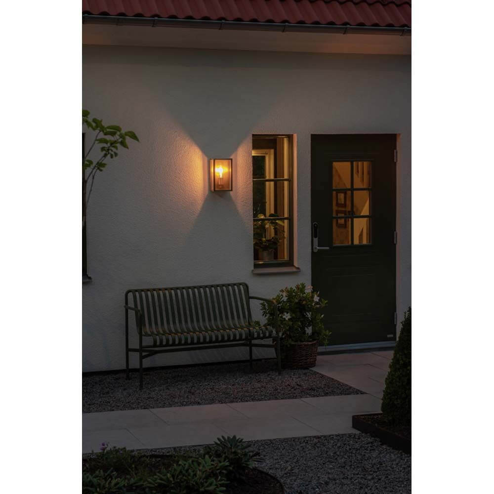 Carpi Wandleuchte Stahl IP44 leuchtet warm und dekorativ an der Wand neben einer Haustür.
