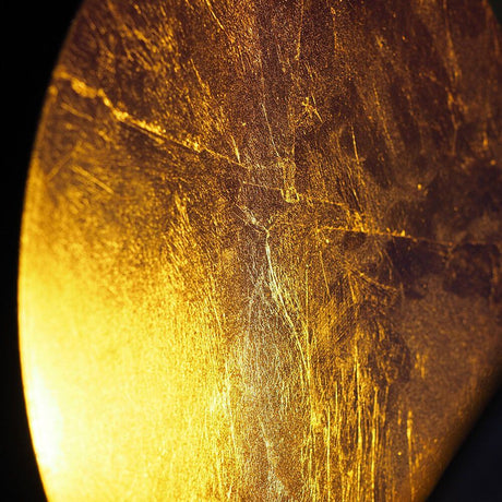 Close-up of the golden surface of the Catellani & Smith Lederam W 25 LED wall light.