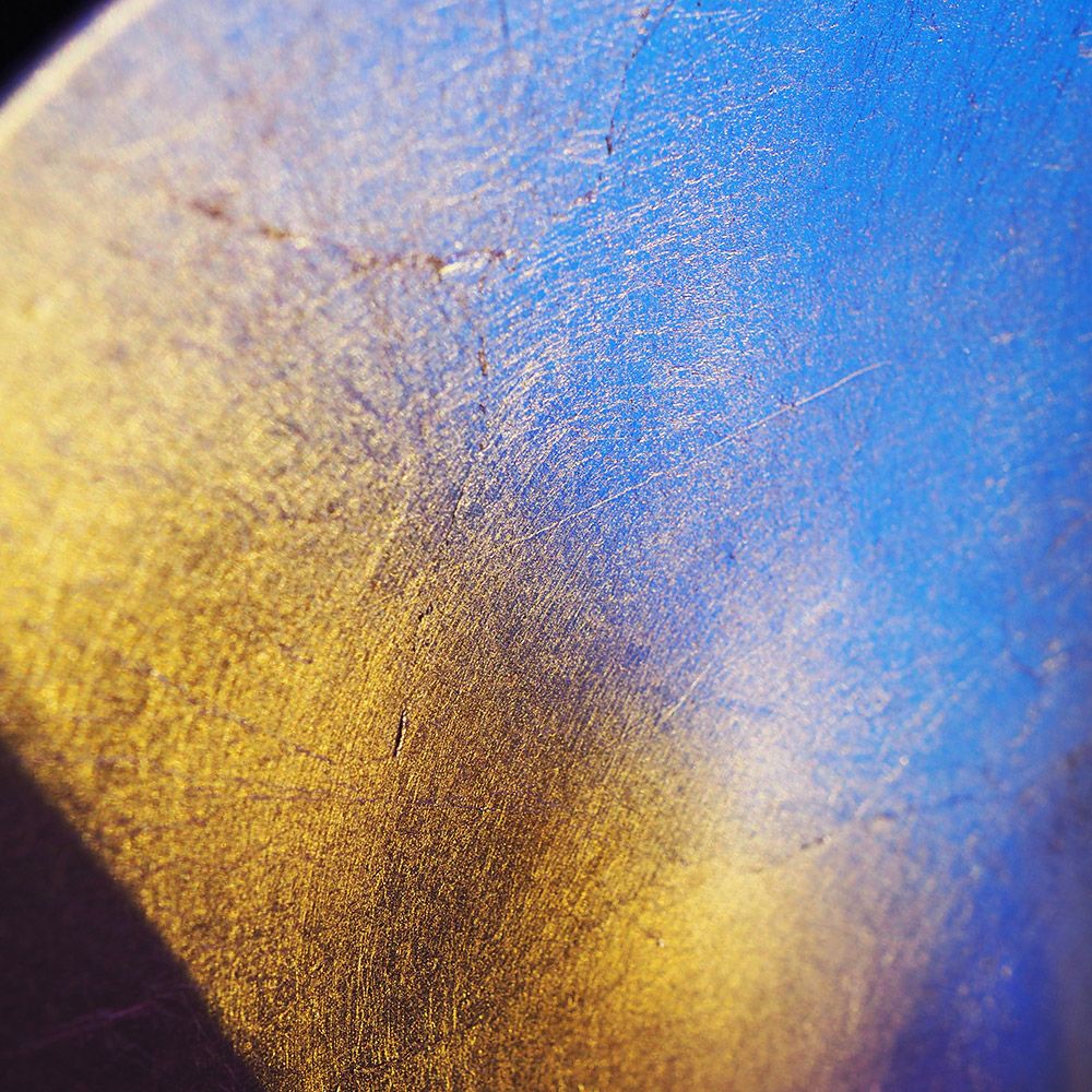Nahaufnahme einer metallic Oberfläche mit goldenen und blauen Farbtönen.