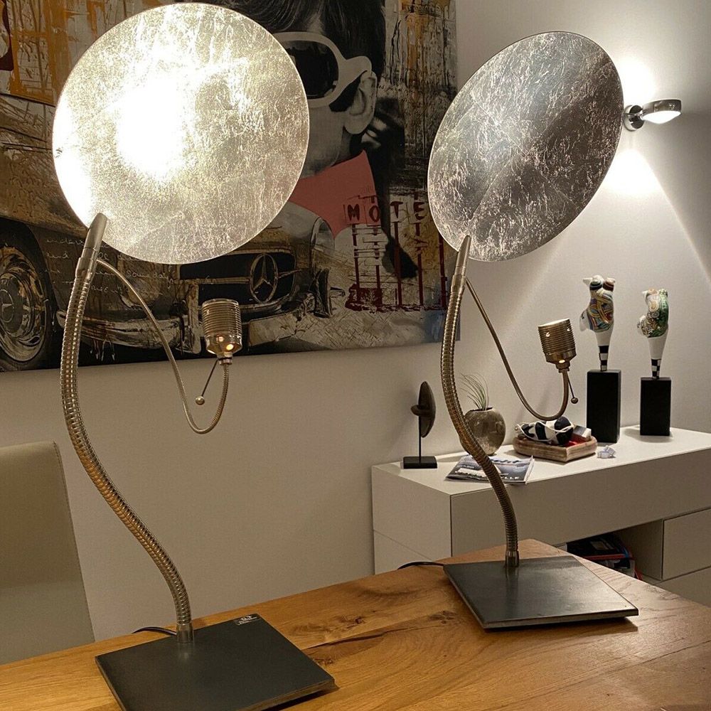 Catellani & Smith Luce d’Oro T LED Tischlampe auf einem Holztisch, erzeugt warmes, indirektes Licht.