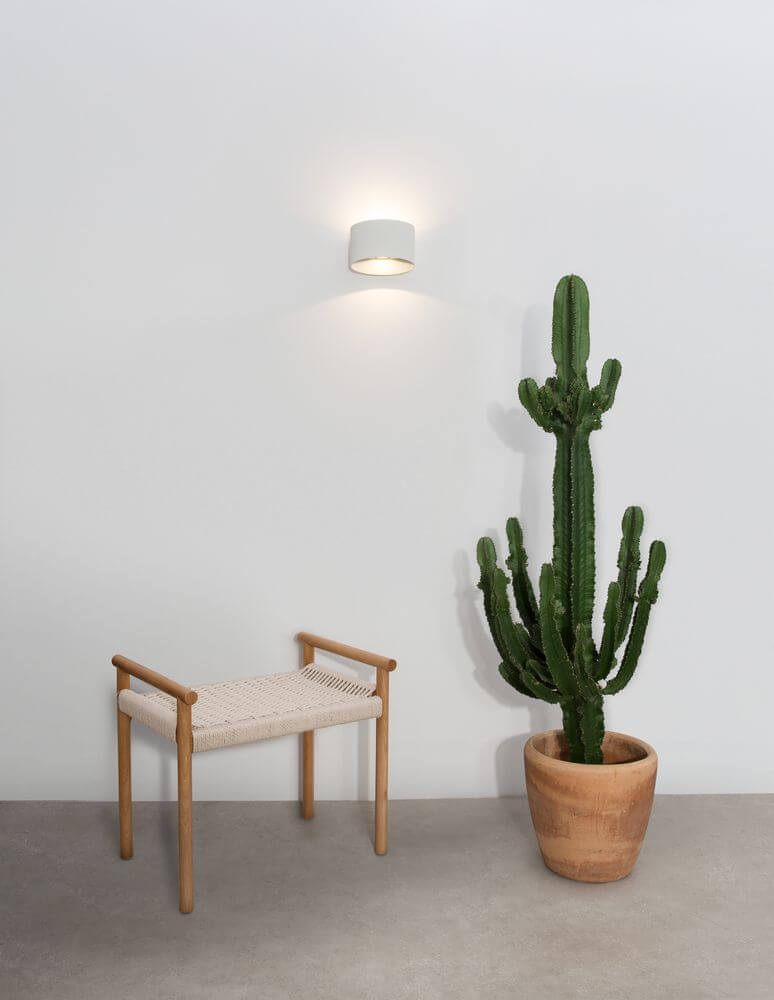 Chez LED Außenwandleuchte Oval 3000K Weiß IP54 an einer Wand neben einem Kaktus und Holzstuhl.