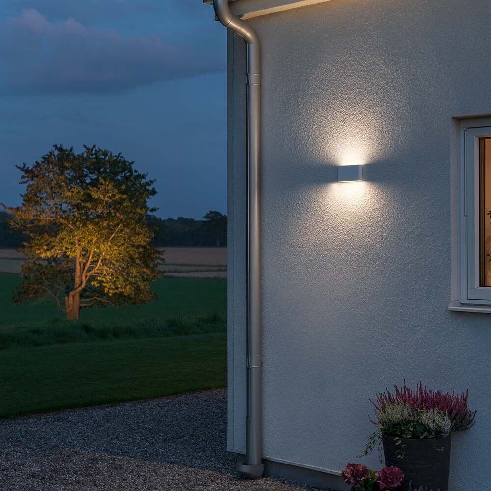 Chieri LED Außen-Wandleuchte Weiß, opales Acrylglas an der Wand eines Hauses bei Dämmerung.
