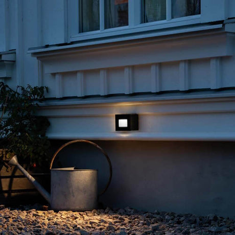 Chieri LED Außen Wandleuchte in Schwarz, montiert an einer Wand, beleuchtet den Außenbereich.